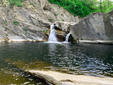 Small mountain waterfall surrounded of rocks and beautiful nature. Kapinovo waterfall in Bulgaria.の写真素材