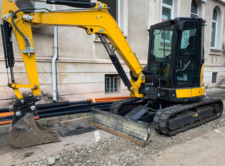 Backhoe with a bucket stands at a construction site. Rebuilding and renovating city street.