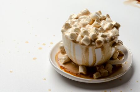 Hot chocolate with mini marshmallow and cinnamon in a white cup on a plate