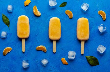 Orange  with juice on a blue bacground. Ice pops, flat layの写真素材