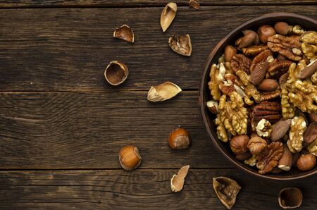 hazelnut almonds pecan nuts in bowl on wooden table background