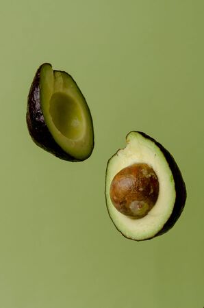 Half avocado flying on pastel green background. Minimalism and objects