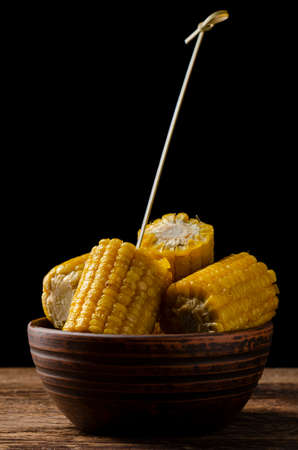 Fresh roasted or grilled corncobs served on a bowl on black backgroundの写真素材