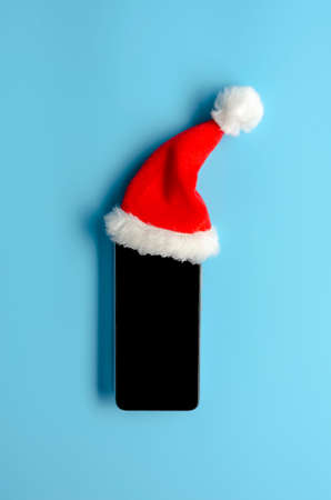 Smartphone in christmas hat on blue backgroundの写真素材