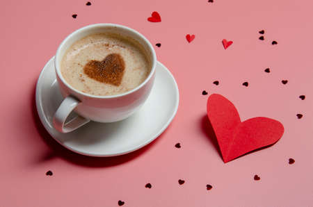 Valentines day. Cup of coffee and papper heart on pink background