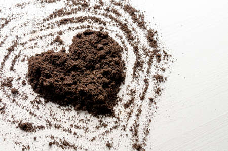 Heart shaped dry soil on white wooden background. Earth day concept.の写真素材