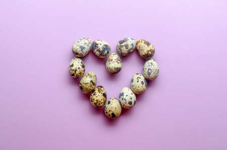 Quail eggs in the shape of a heart. Quail eggs on violet backgroundの写真素材