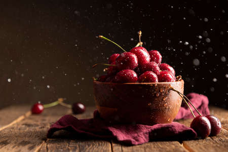 Cherries on wooden table with water drops on the bowlの写真素材