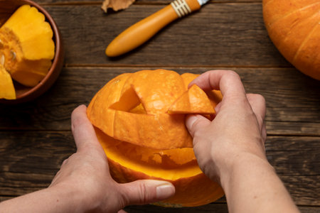 Woman carving pumpkin for Halloween on wooden tableの写真素材