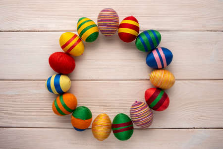 Handcrafted Easter decorations from thread. Multicolor eggs made from yarn and thread on wooden background.の写真素材