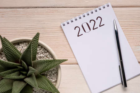 2022 Goals. Notepad with pen on white wooden table.