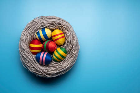Handcrafted Easter decorations from thread. Multicolor eggs made from yarn and thread on blue background.の写真素材