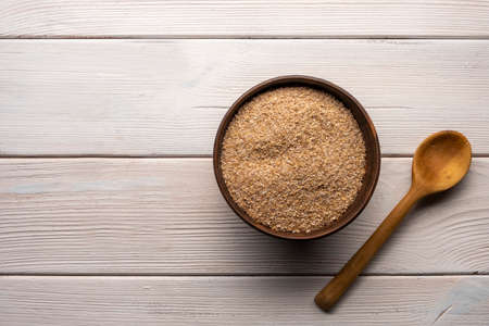 Wheat bran in bowl on a white wooden table.の写真素材