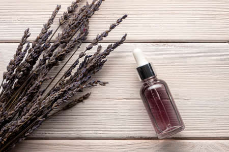 Glass bottle of lavender essential oil with dried lavender on white wooden table. Aromatherapy, spa.の写真素材