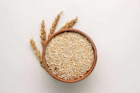Spelt bran and grains in clay pot isolated on white backgroundの写真素材
