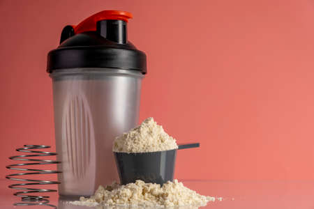 Shaker and protein powder on pink background. sports nutrition concept