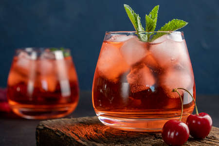 Cherry cocktail in glass on blue background. Summer iced beverage.の写真素材