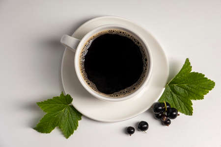 Coffee cup with black currant on a white background. New taste of coffee.