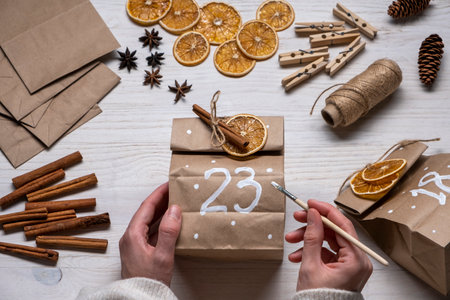 Womans hands making advent calendar from craft paper with dry oranges and cinnamon.の写真素材