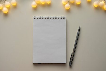 White sheet of notebook on white table with garland. Concept planning, wish list for the new year.の写真素材