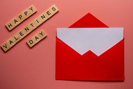 Red paper envelope with blank white note mockup inside and Valentines hearts on pink background.の写真素材