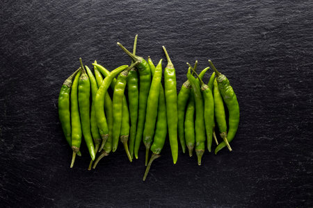 Green chili peppers on dark stone background.の写真素材