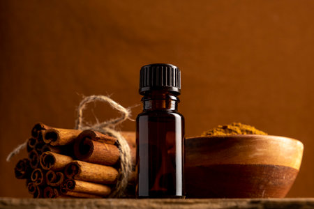 Essential cinnamon oil in a small bottle, ground cinnamon and cinnamon sticks on old wooden...