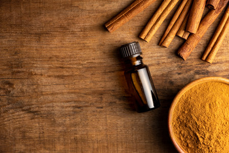 Essential cinnamon oil in a small bottle, ground cinnamon and cinnamon sticks on old wooden background.の写真素材