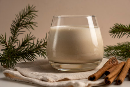 Traditional Christmas drink Eggnog with cinnamon on white table. Hot beverage for winter holidays.の写真素材