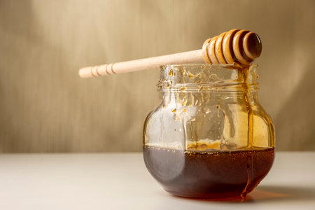 Honey dripping from honey dipper on yellow background.の写真素材