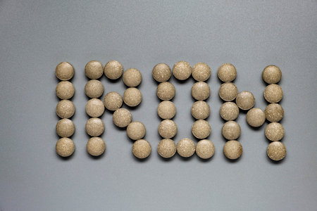 Round green tablets of iron supplements on gray background.の写真素材