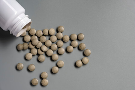 Round green tablets of iron supplements on gray background. Health medicationの写真素材