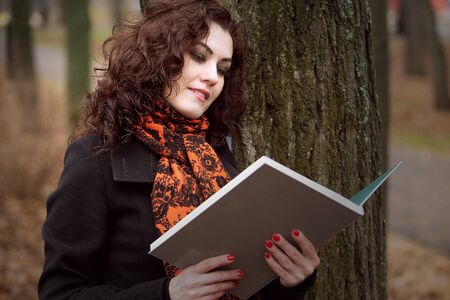 Portrait of a beautiful blue-eyed girl reading a book close-up. A woman in a dark coat and a bright...