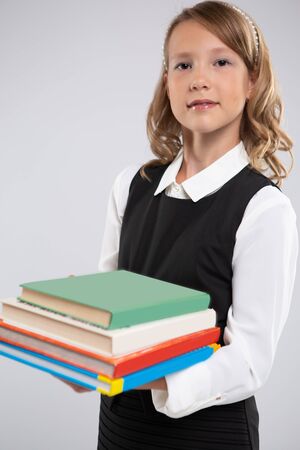 Expressive portrait of a smiling beautiful young schoolgirl with school textbooks.Portrait of a girl on an isolated backgroundの写真素材