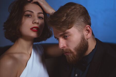 a young woman proudly looks forward while her man sadly looks down to the sideの写真素材