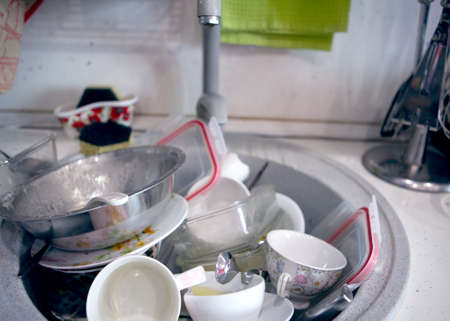 A large pile of dirty dishes in the kitchen sink ready to be washedの写真素材