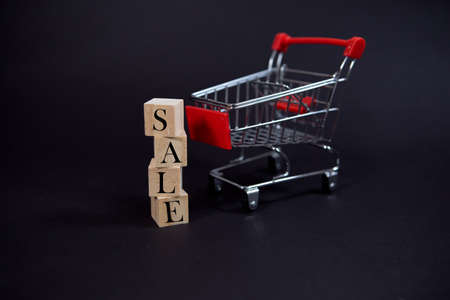 wooden cubes with the inscription - Sale on a black background with a shopping basket, sales concept, business management, crisisの写真素材