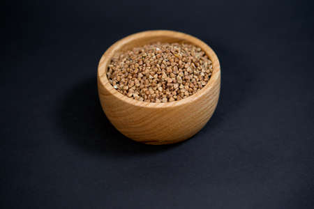 Buckwheat in a stylish wooden Cup on a black background.の写真素材