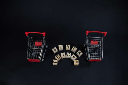 wooden cubes with the inscription-Black Friday on a black background with a shopping basket, sales...