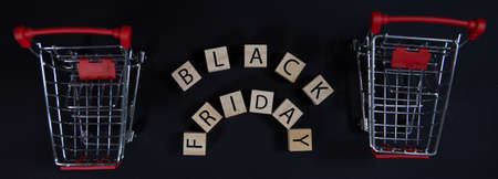 Black Friday concept of a sale in a store, cubes with the inscription black Friday and a supermarket cart on a black background. Photo from the topの写真素材