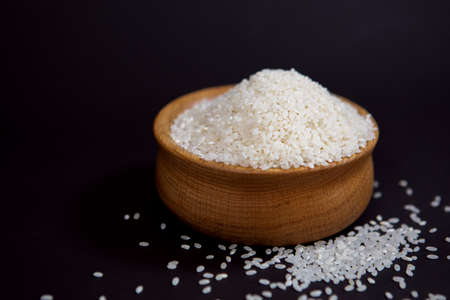 white rice in a beautiful wooden Cup on a black background