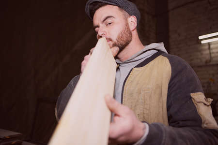 A male carpenter inspects the correct geometry of a wooden Board. Photo of a working carpenter in the carpentry industryの写真素材