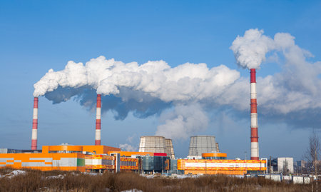 Factory main pipes that emit a lot of smoke into the atmosphere. The blue sky is obscured by smoke from factory chimneysの写真素材