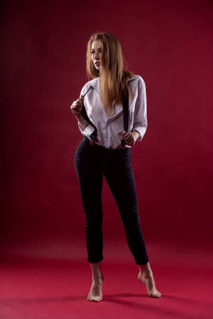 fashionable sexy young woman posing in an unbuttoned shirt on a red backgroundの写真素材
