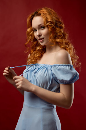 Portrait of a sexy red-haired woman with long hair on a red background. The perfect girl with blue eyes, beautiful clear skin, beautiful natural makeup, red hairの写真素材