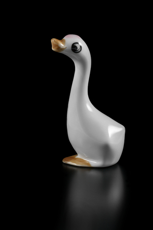 Ceramic figurine of a white goose on a black backgroundの写真素材