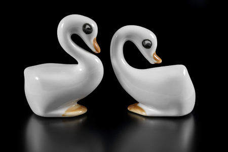 Ceramic figurines of white geese on a black backgroundの写真素材
