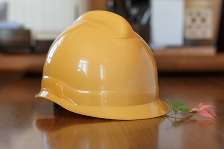 Construction protective helmet and autumn leaves on a tableの写真素材