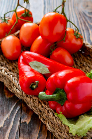 Ripe red vegetables in a wicker plate on the tableの写真素材