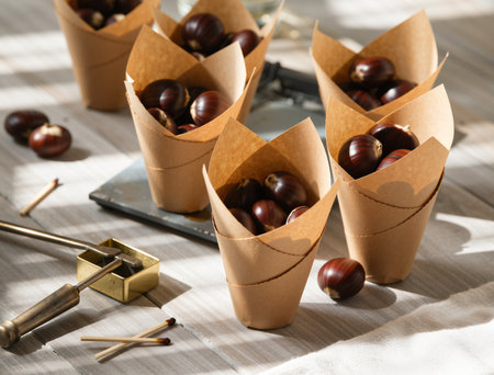Horse chestnuts in paper cups on wooden table, closeupの素材